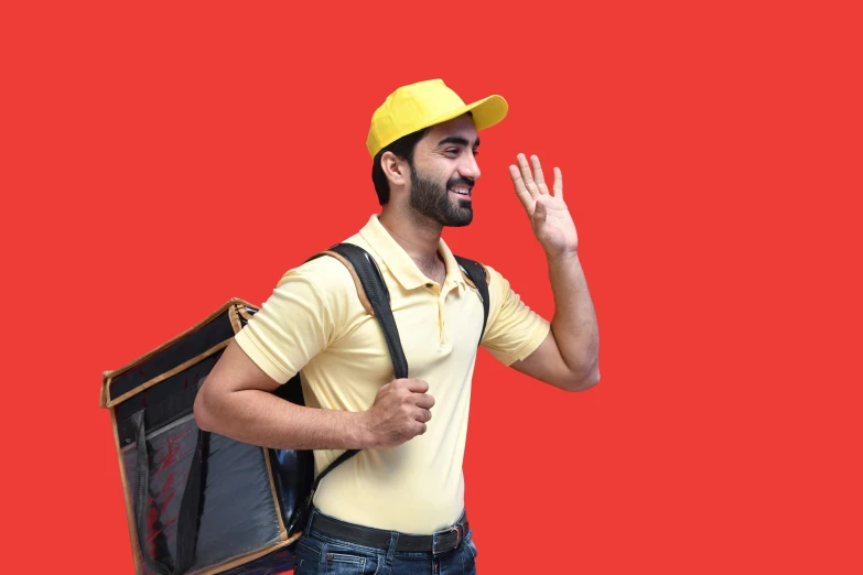 a man wearing a yellow hat and a backpack waving