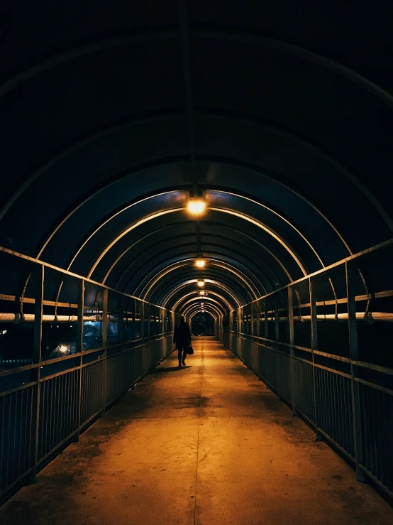 people are walking under a tunnel at night