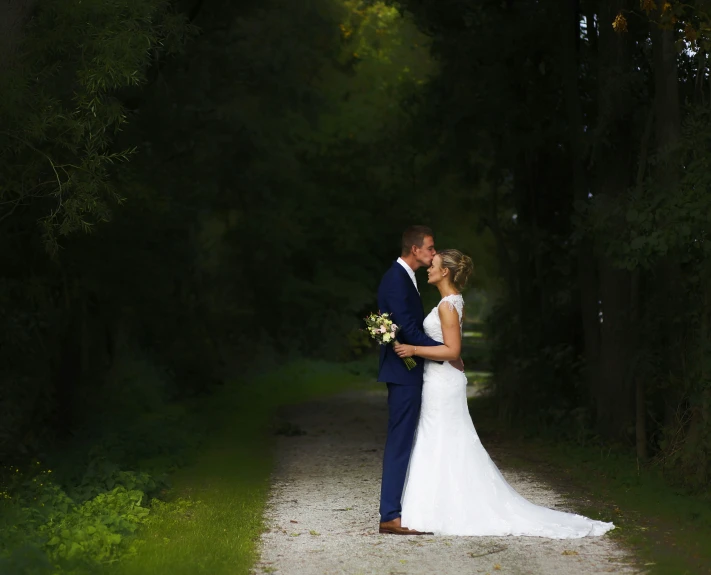 a bride and groom emcing on the path in the woods
