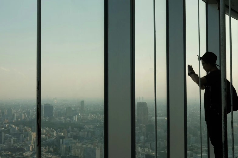 man in suit and goggles looking out from tall building