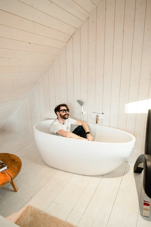 a man sits inside of a bath tub in a bathroom