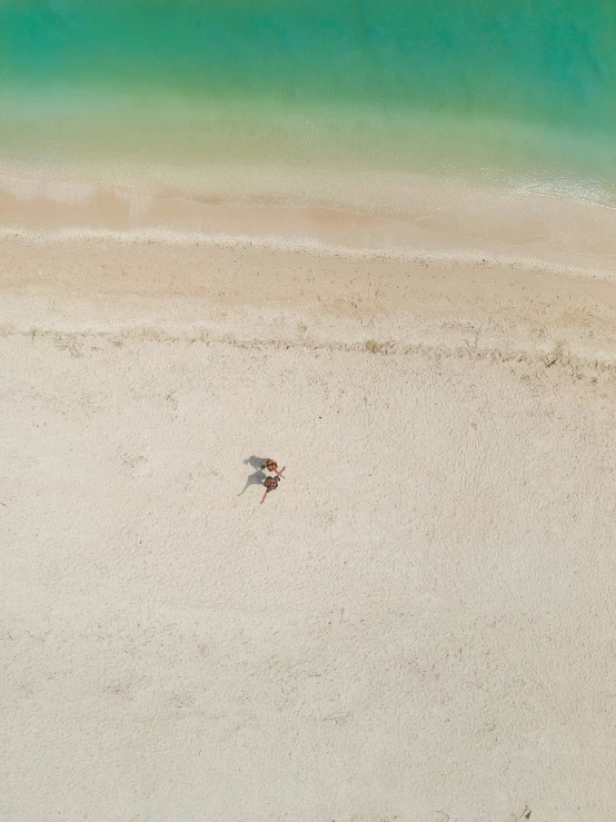 a sandy beach with green water and two umbrellas