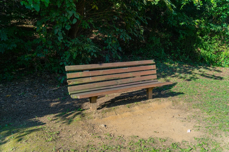 a bench in the middle of some dirt and a tree