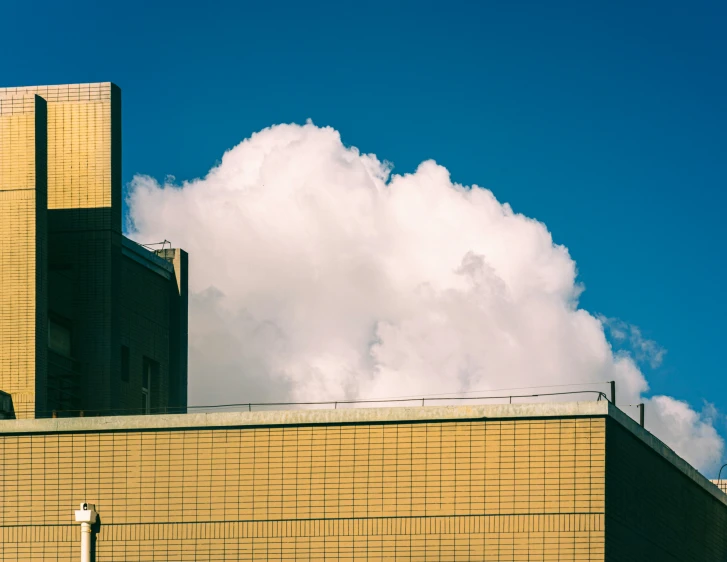 tall brick building with a large white fluffy cloud behind it