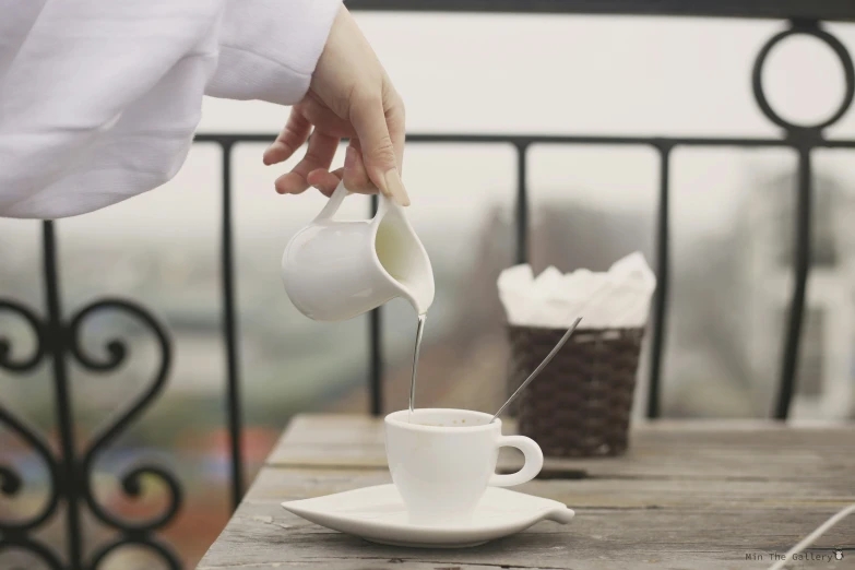 a person pours tea into a white tea cup