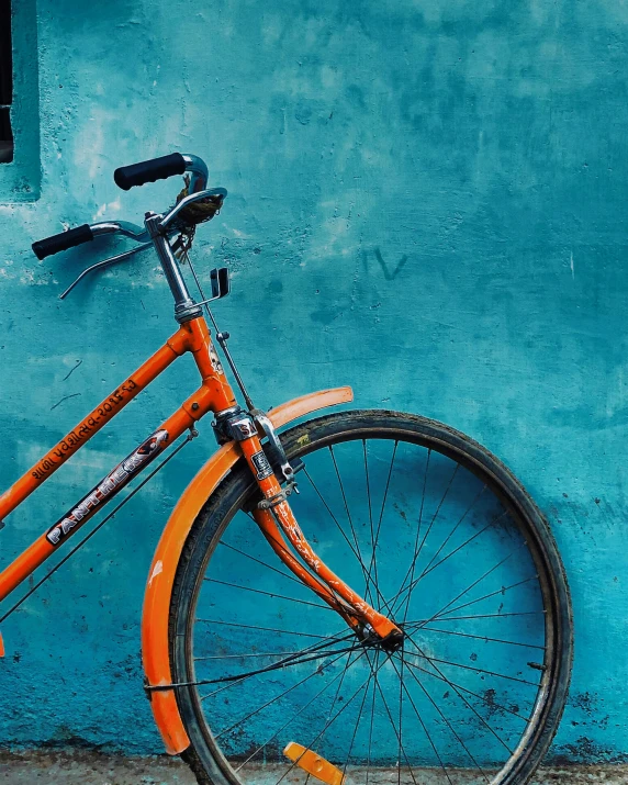 a bike parked by a blue wall near a wall