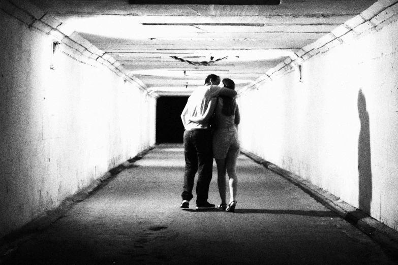 black and white pograph of two people standing in a dark corridor