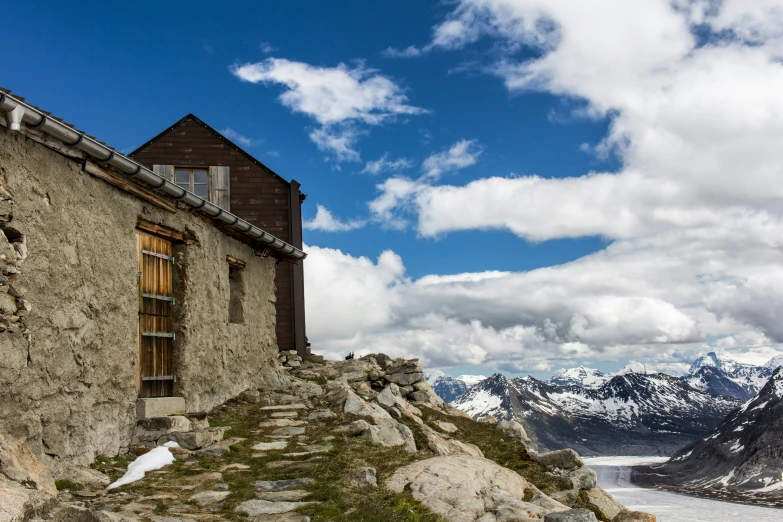 this house is sitting on a rock, overlooking a mountain