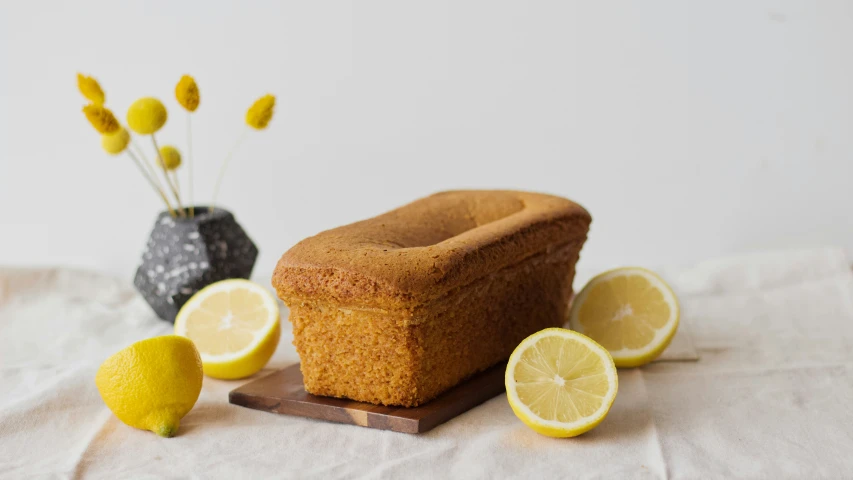 a bread loaf that has been cut into slices next to lemons