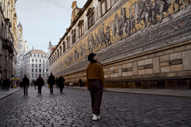 the woman walks down the cobblestone street near several other people