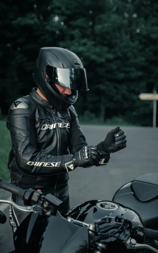 the motorcycle rider wears leather gear and is checking his hand on the bike