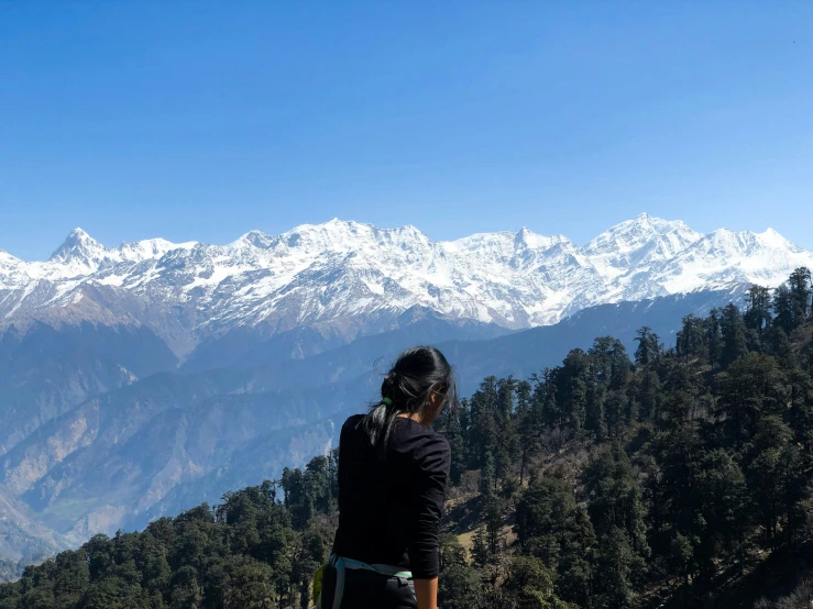 woman standing alone on top of mountain overlooking the view