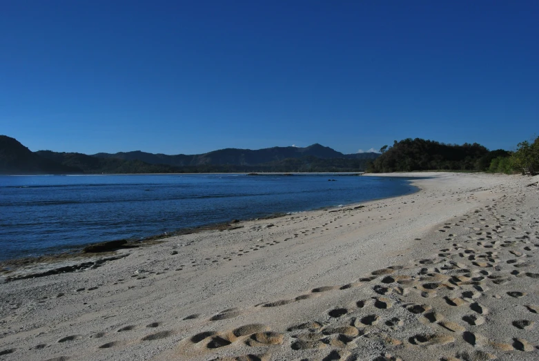 two footprints in the sand leading towards an ocean