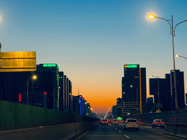 a city street with some cars driving on it at dusk