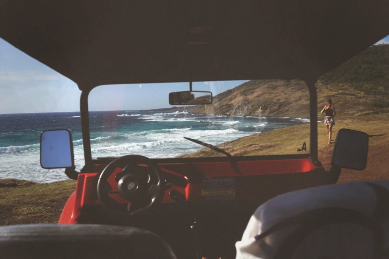 a view from inside a vehicle shows people riding bicycles and surfing