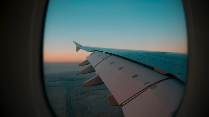 an airplane wing in flight over a desert