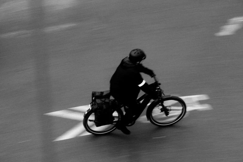 black and white pograph of man riding bicycle in street