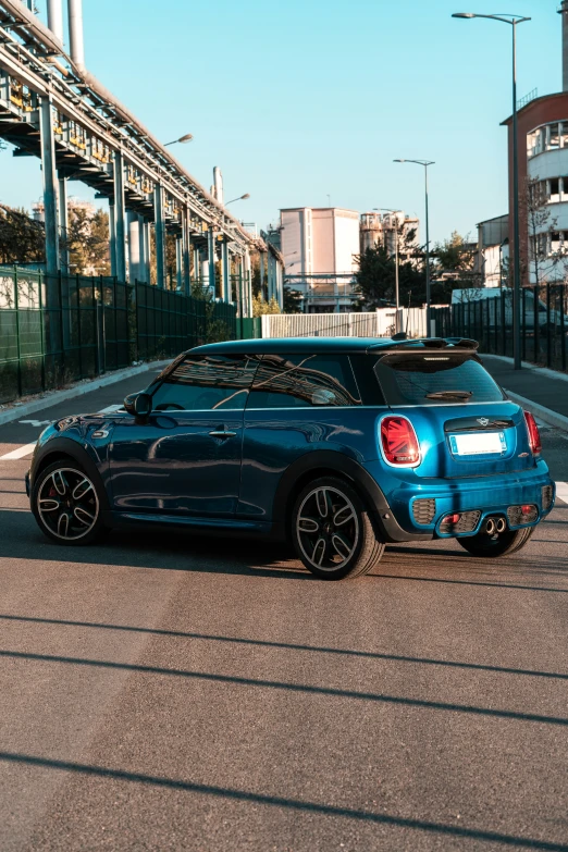 the blue hatchback is parked beside the black mini cooper