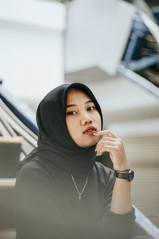 a woman sitting in an escalator wearing a hijab