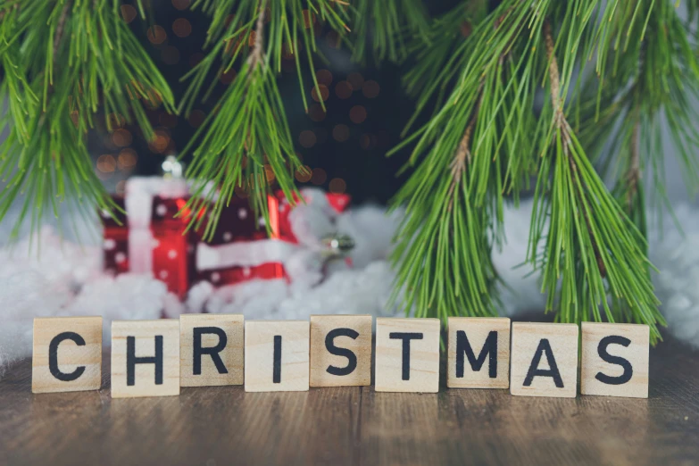 scrabbled letter blocks spelling christmas surrounded by pine needles