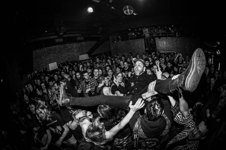 a crowd is watching a man performing in a crowded club