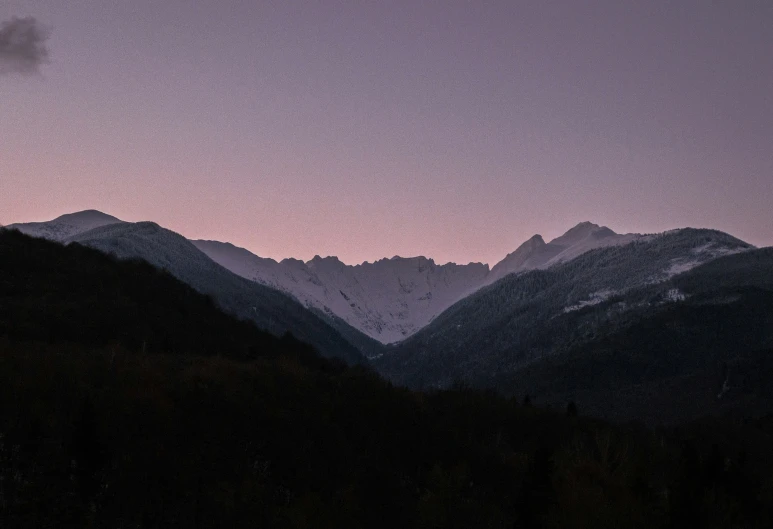 the silhouette of mountains against a cloudy sky