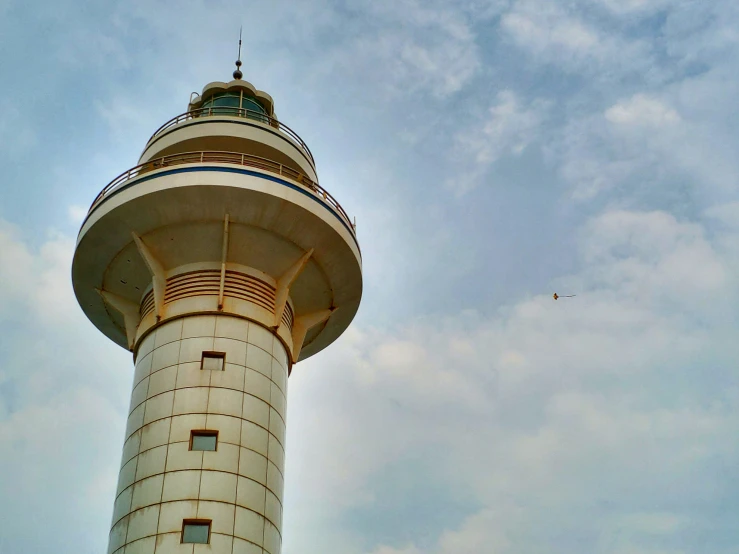 two people stand next to a very tall lighthouse