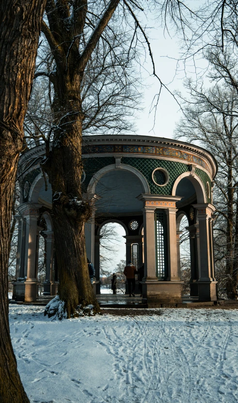 a gazebo covered with snow sits next to trees