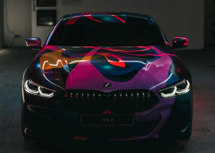 the front end of a black car with colorful paint