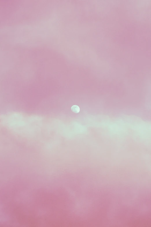 a pink sky with the moon in the distance