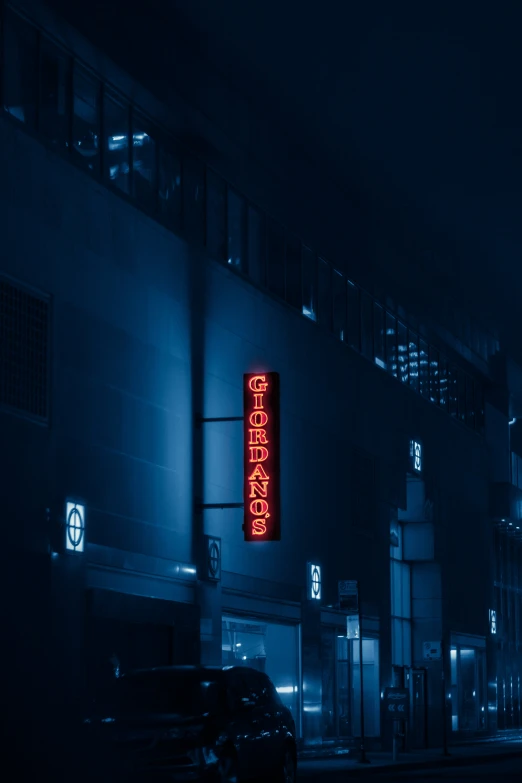 a building in the fog with a neon sign in front