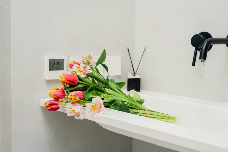 a bouquet of flowers sitting in a bathtub next to thermostaer