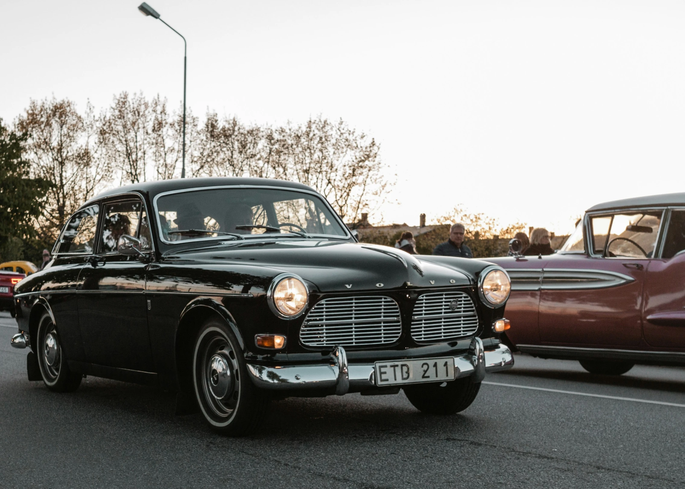 an old fashioned car driving down the road