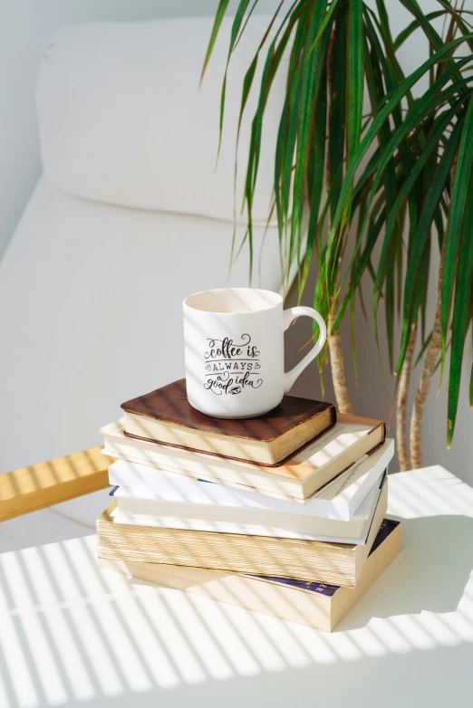 a stack of books with a coffee cup on top