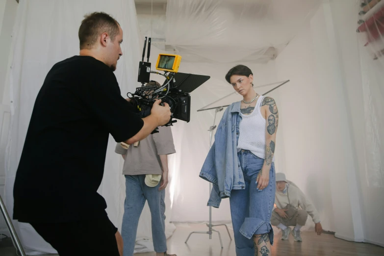 a woman behind a camera with a man standing next to it