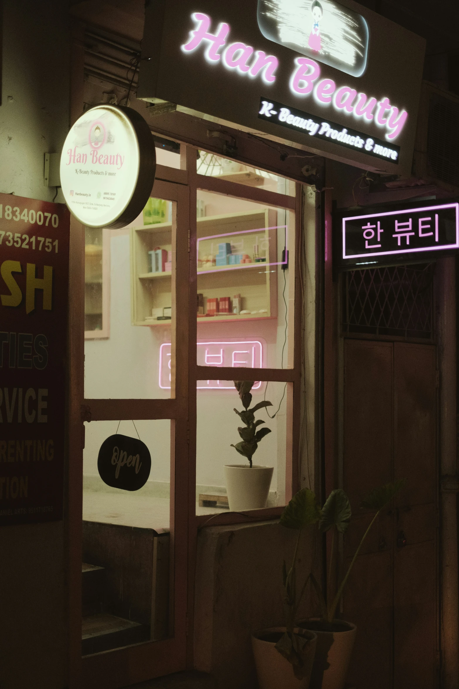 a store front with neon lights and a potted plant