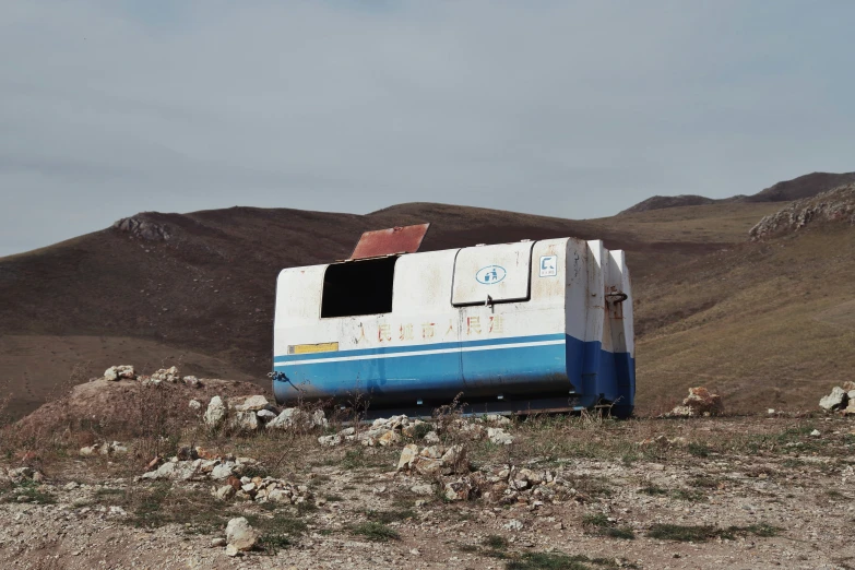 old abandoned bus in rocky terrain with mountain background