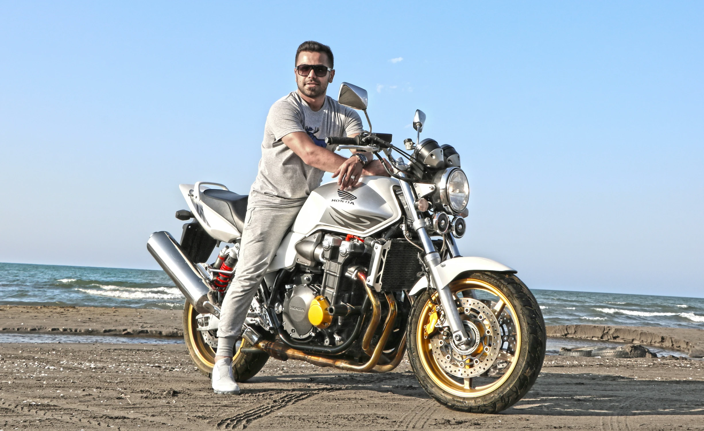 man sitting on motorcycle near beach in front of ocean