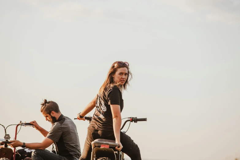 two young adults are on motorcycles in an open field