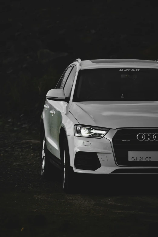 the front of an audi suv parked on the side of a dirt road