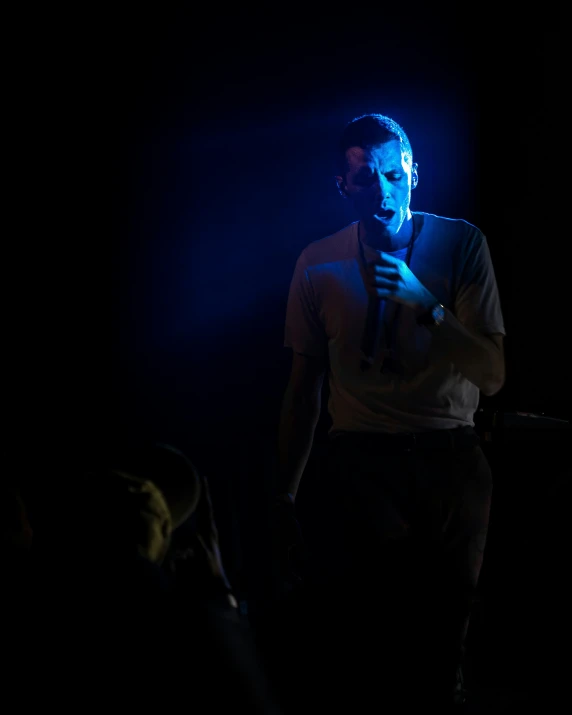 the man is talking into his microphone in the dark