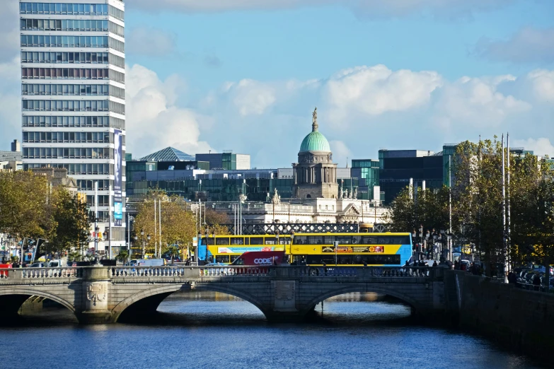 a yellow bus is crossing the bridge over water