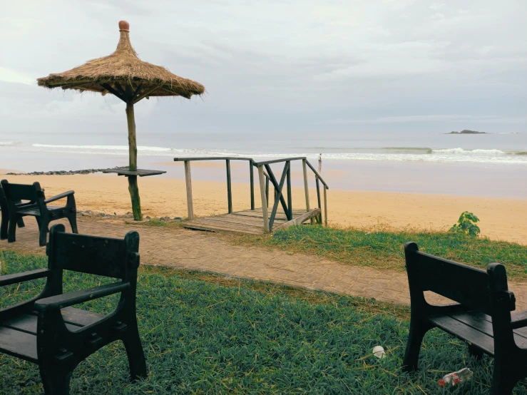 two black wooden benches on a sandy beach