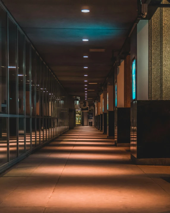 long hallway with dark glass walls lit by lights