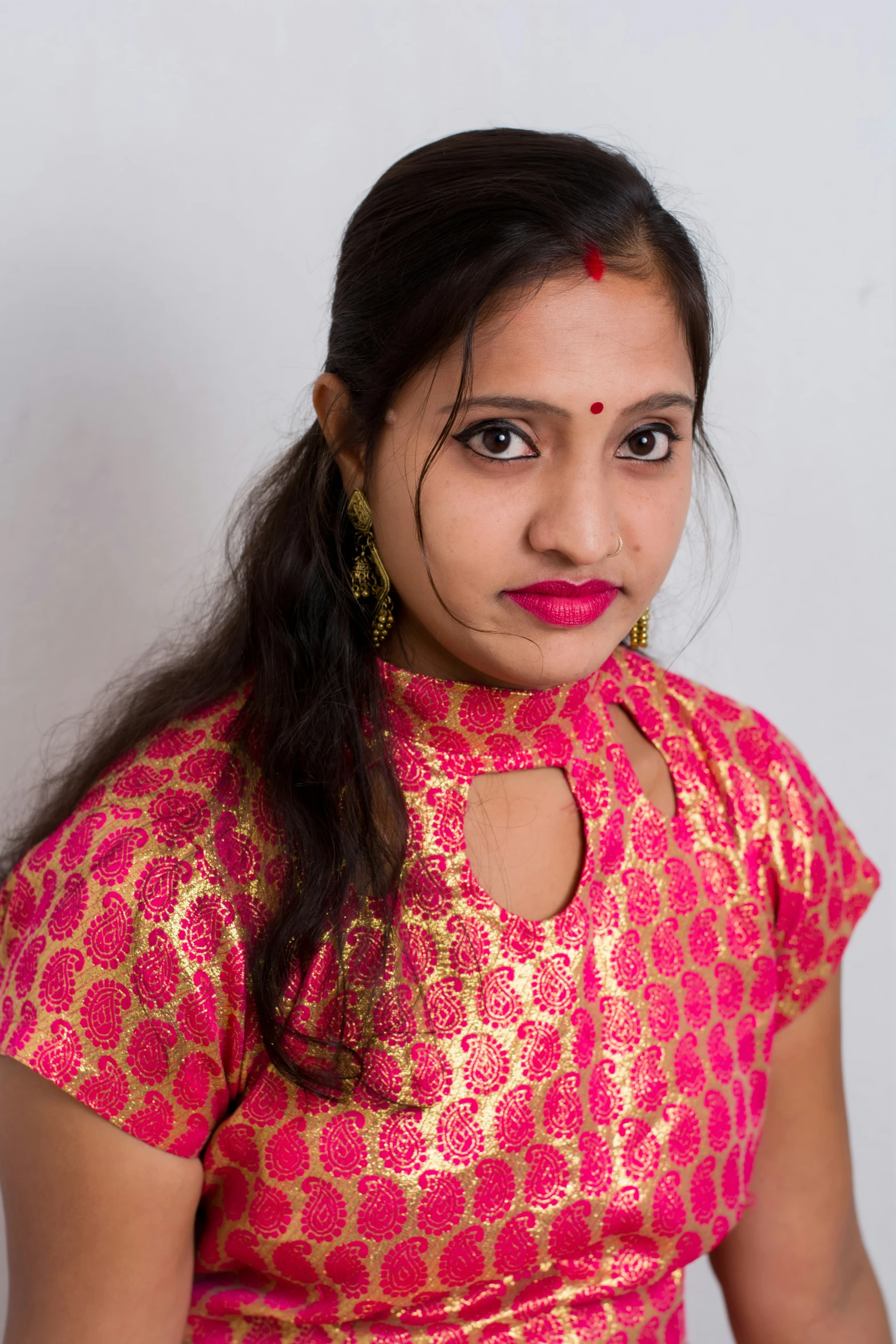 a woman in pink blouse standing in front of white wall