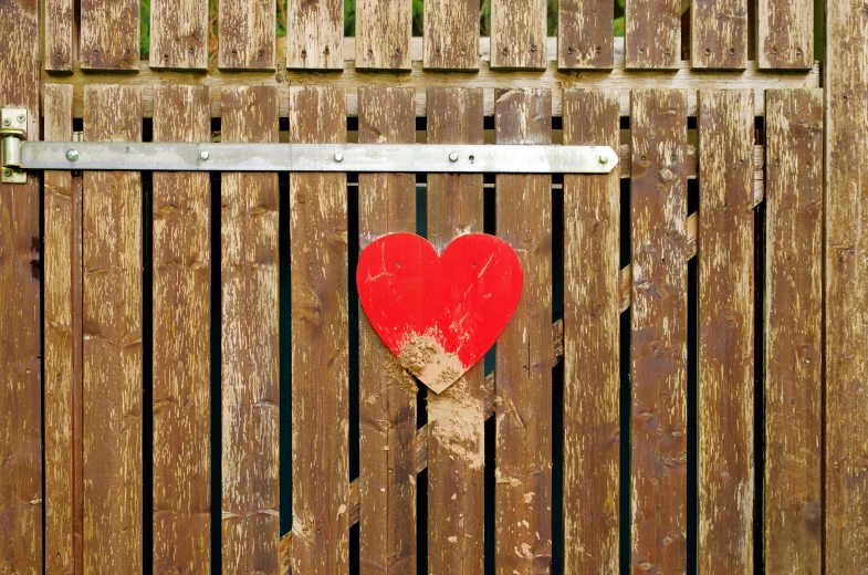 the door is boarded up to reveal a red heart on a wooden board