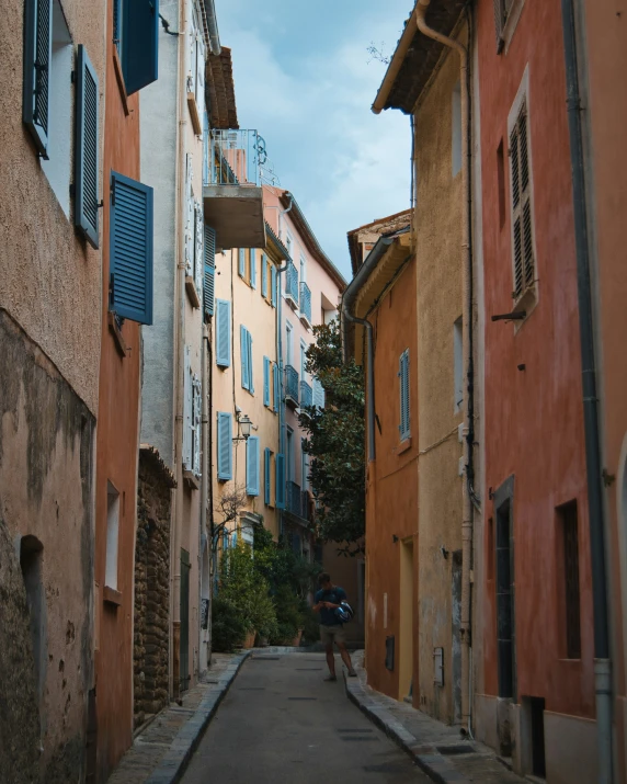 people walking down a narrow city street next to some tall buildings