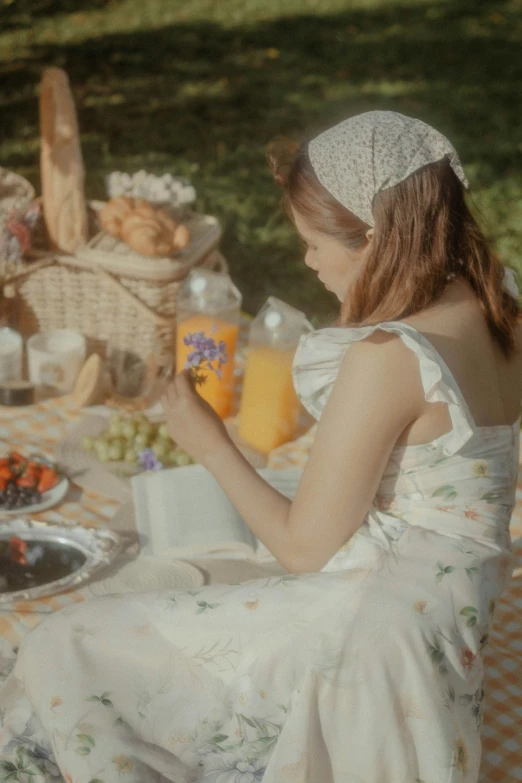 a woman in a dress is sitting down in front of a table full of picnic foods