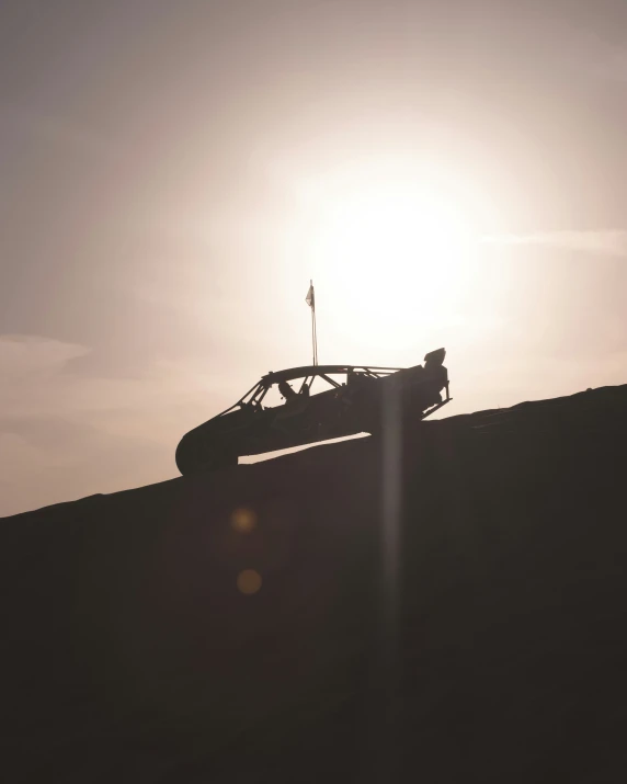 an off road vehicle moving up a hill as the sun is low