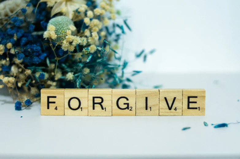 scrabble block with the word live spelled in letters with dried flowers